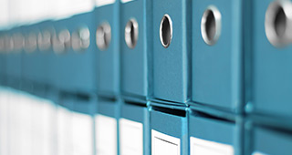 Blaue Aktenordner mit runden Metallösen an der Seite, in einer Reihe aufgereiht.